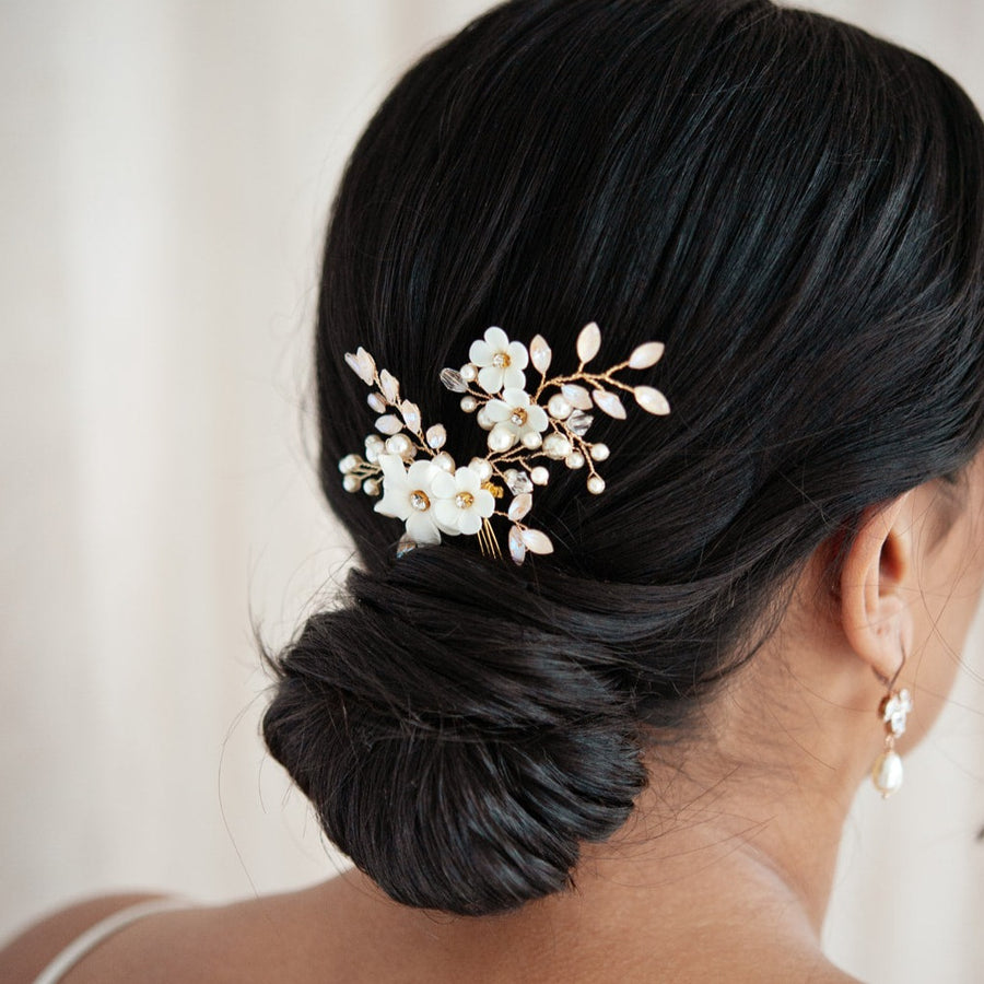 Bride wearing sleek updo with blush and floral bridal hairpins. 