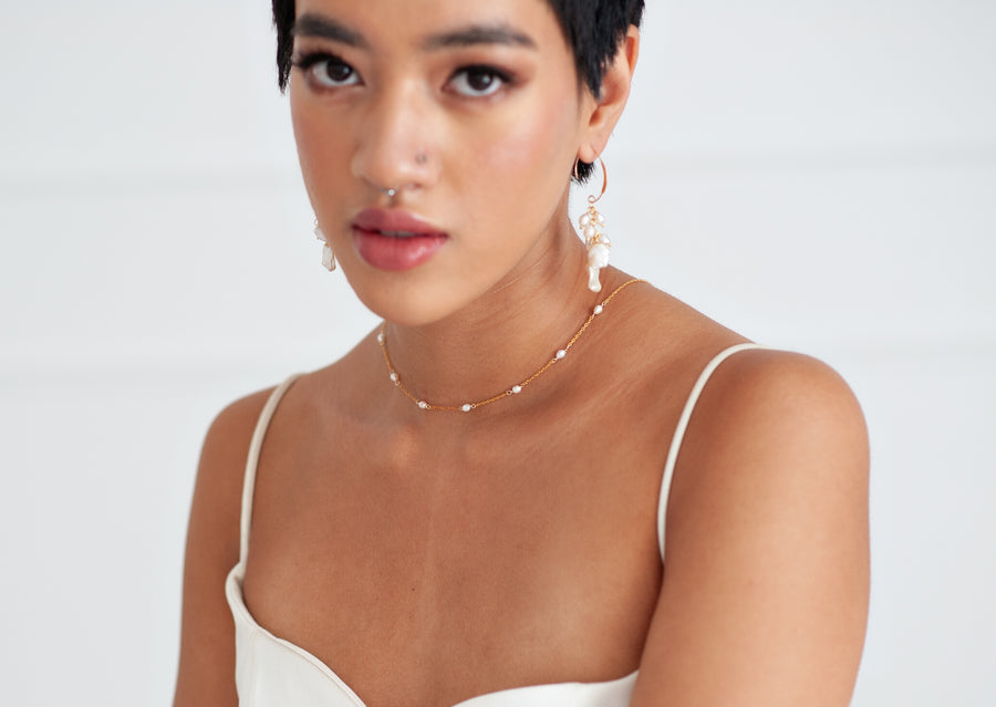 Bride wearing a simple gold chain and pearl bridal necklace. 