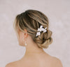 A set of 3 floral bridal pins with pearl detailing in a bride's wedding updo.
