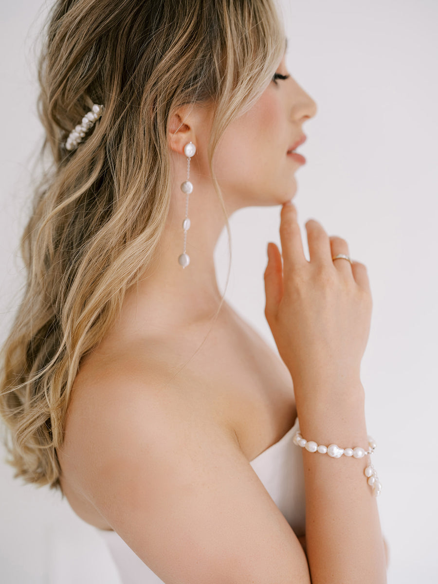 Bride wearing long pearl bridal earrings with matching pearl wedding bracelet.