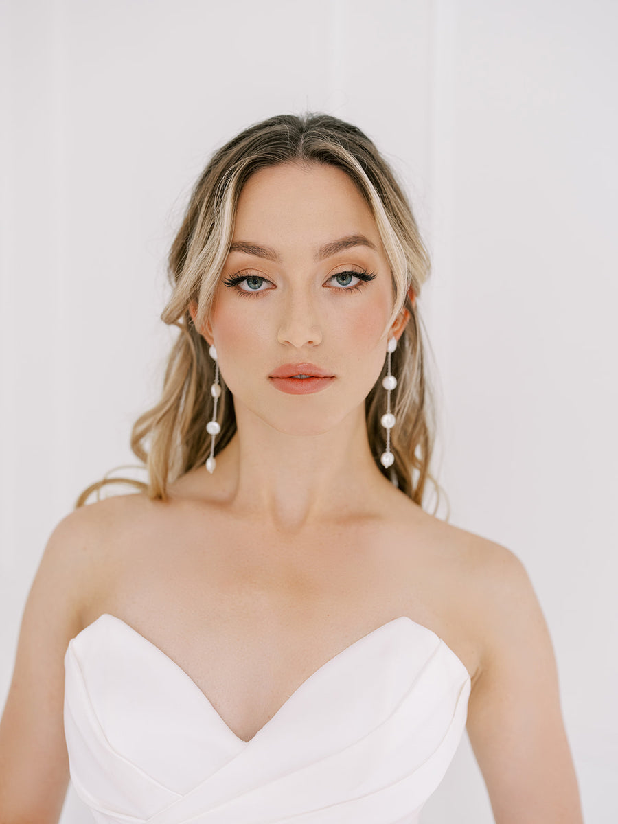 Bride wearing on trend long pearl bridal earrings.