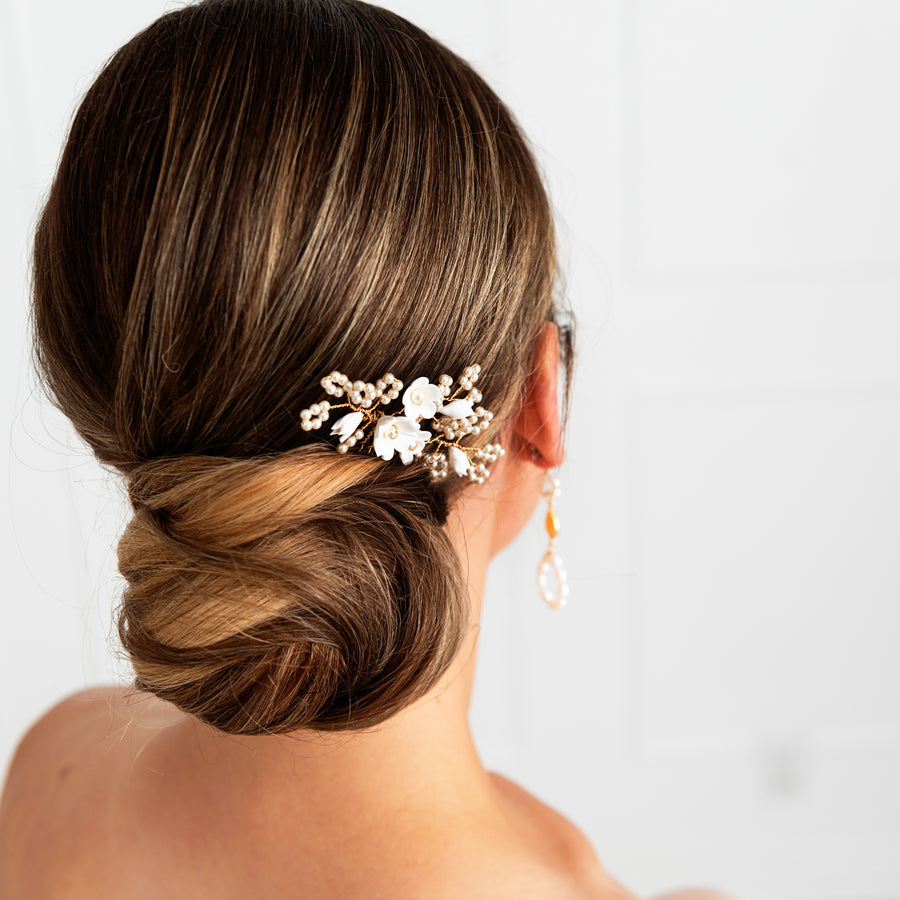 Bride wearing delicate pearl and flower bridal comb in an elegant updo