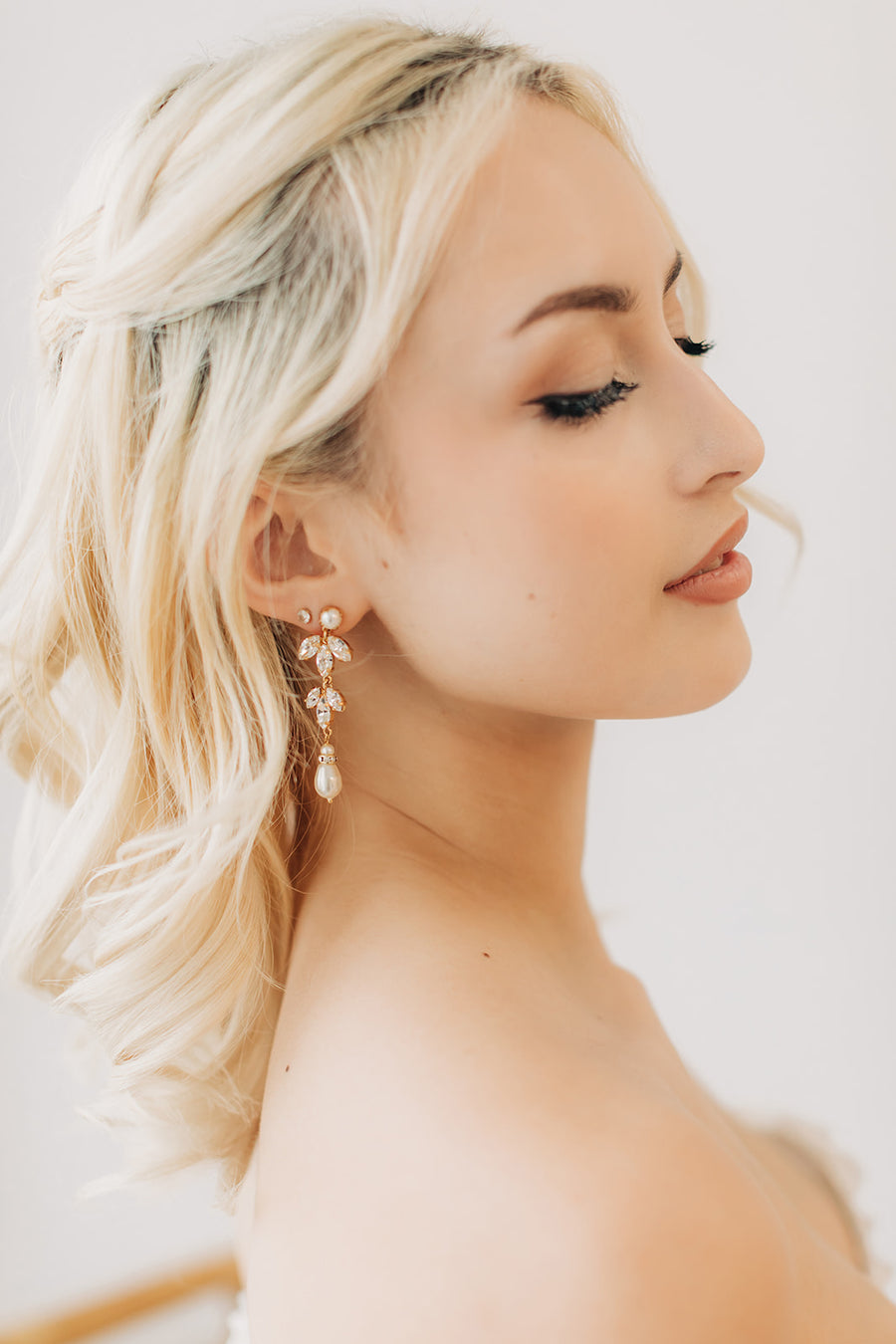  A bride with long blonde hair wearing a Swarovski Crystal and Pearl Bridal Statement Earring by Joanna Bisley Designs. 