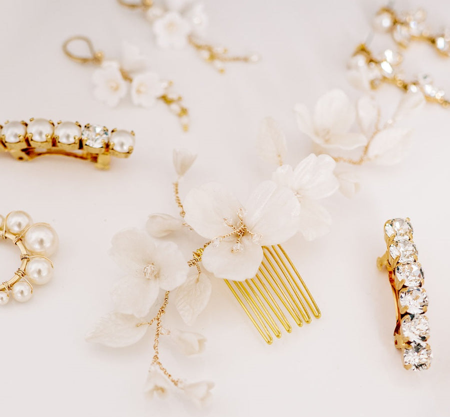 A Flat Lay picture of gold and Pearl earrings and floral bridal comb. 