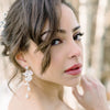 Bride looking over her shoulder wearing long floral bridal statement earrings. 