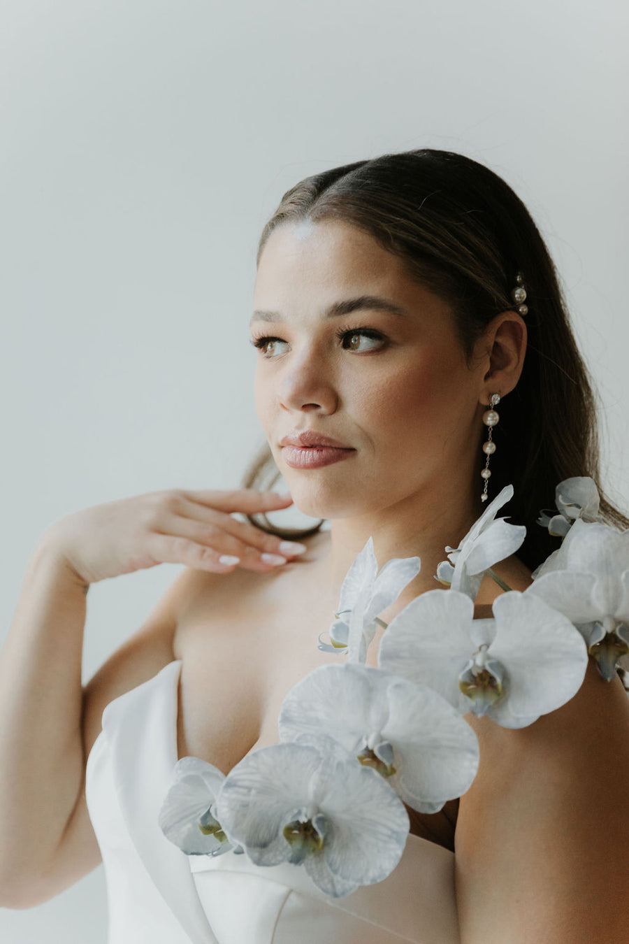 Bride with elegant wedding dress wearing long pearl bridal earrings with Swarovski Crystal stud.