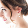 Bride with bridal hair updo wearing a modern pair of hoop and pearl bridal earrings by Joanna Bisley Designs.