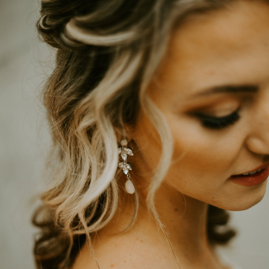 Bride with hair down wearing a pair of luxury crystal bridal earrings with blush drops.